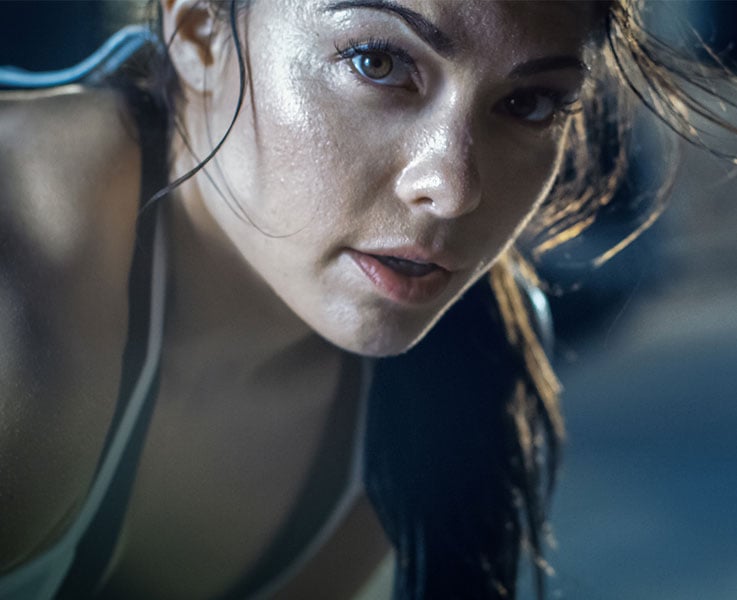 Close-up Shot of a Beautiful Athletic Woman Looks into Camera. She's Tired after Intensive Cross Fitness Exercise.